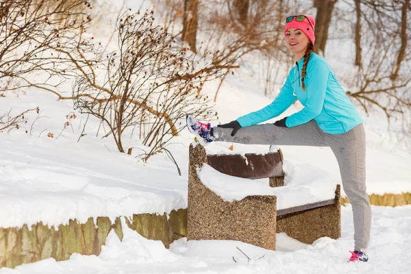Menina que se estende no banco no inverno — Fotografia de Stock