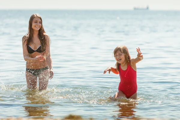 Niña y madre en agua de mar. Diversión — Foto de Stock