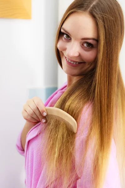 Woman combing her long hair in bathroom — Stock Photo, Image