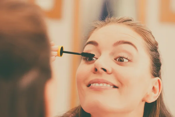 Woman applying black eye mascara to her eyelashes — Stock Photo, Image