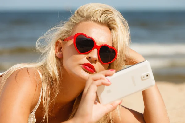 Mujer acostada en la playa de arena usando el teléfono celular —  Fotos de Stock