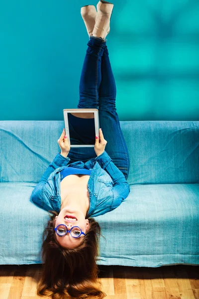 Žena s tabletem relaxační na gauč modré barvy — Stock fotografie