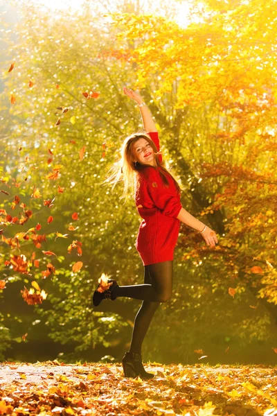Woman relaxing in autumn park throwing leaves up in the air — Stock Photo, Image