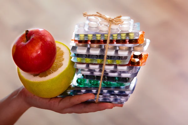 Mano humana sosteniendo pila de píldoras y frutas —  Fotos de Stock