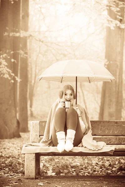Dziewczyna siedzi w parku z parasolem — Zdjęcie stockowe