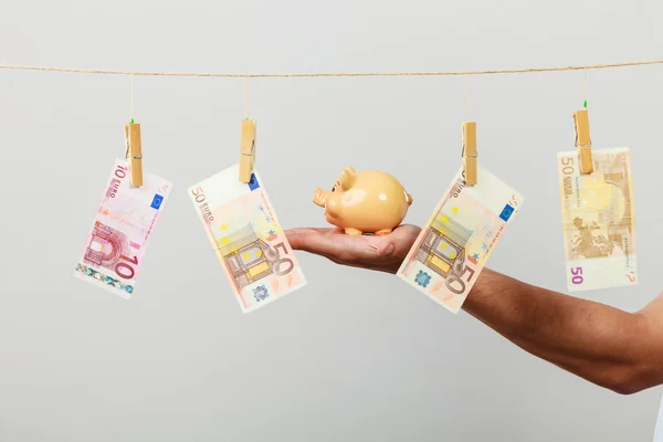 Mannenhand met bankbiljetten en spaarpot — Stockfoto