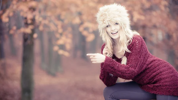 Dość uśmiechający się kobieta w futro zimowe czapki wskazując. — Zdjęcie stockowe