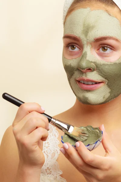 Vrouw met borstel klei modder masker toepassen op haar gezicht — Stockfoto