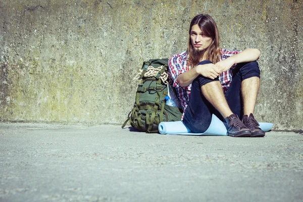 Homme touriste routard assis par grunge mur extérieur — Photo