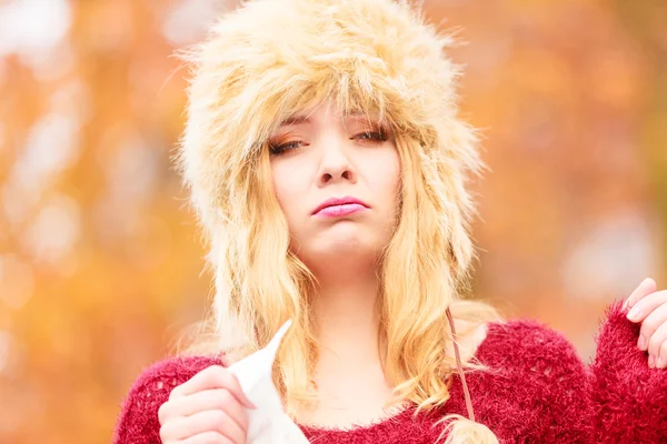 Sick woman in autumn park sneezing into tissue. — Stok fotoğraf