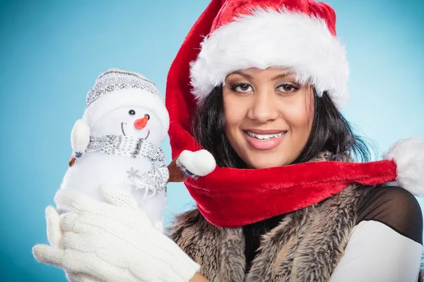 Mujer de raza mixta en sombrero de santa con muñeco de nieve poco . —  Fotos de Stock