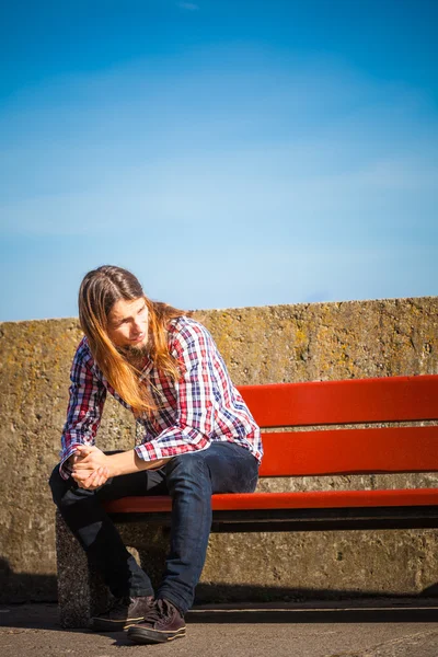 Man long hair sitting on bench outdoor — Stock Photo, Image