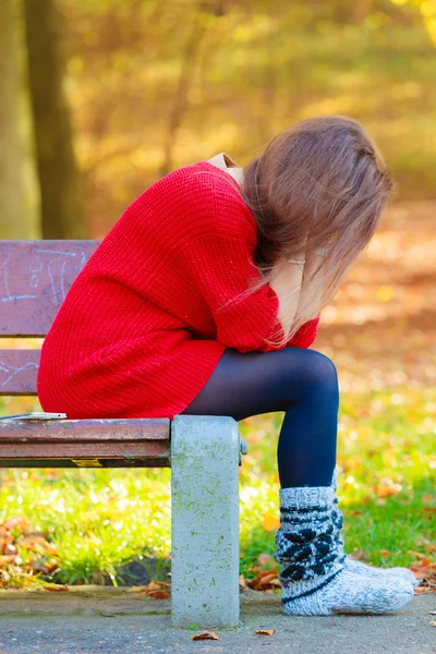 Sorglig kvinna sitter på bänk i parken — Stockfoto