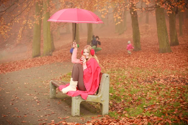 Mädchen sitzt mit Regenschirm im Park — Stockfoto