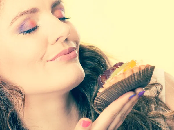 Frau hält Kuchen mit geschlossenen Augen in der Hand — Stockfoto