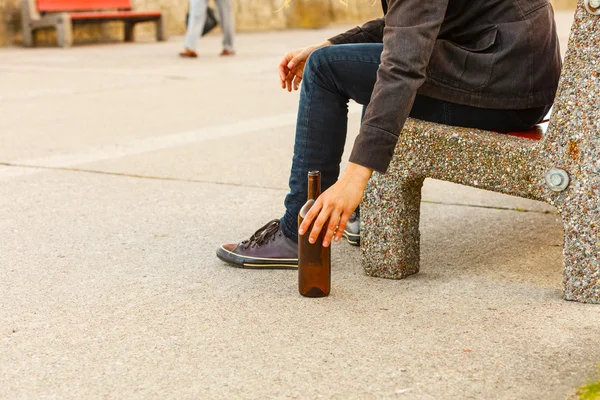 Hombre deprimido con botella de vino sentado en el banco al aire libre — Foto de Stock