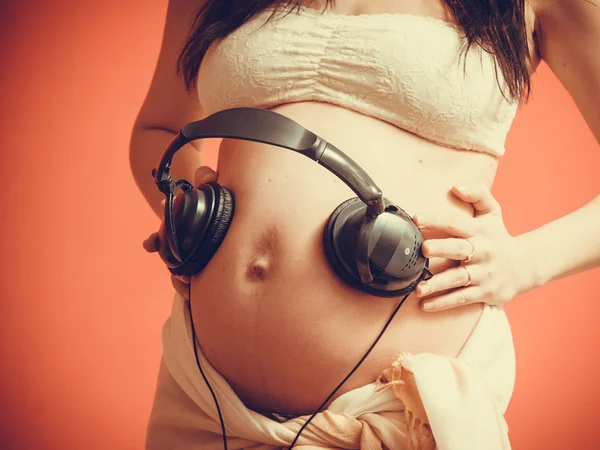 Těhotná žena dává sluchátka na břicho — Stock fotografie