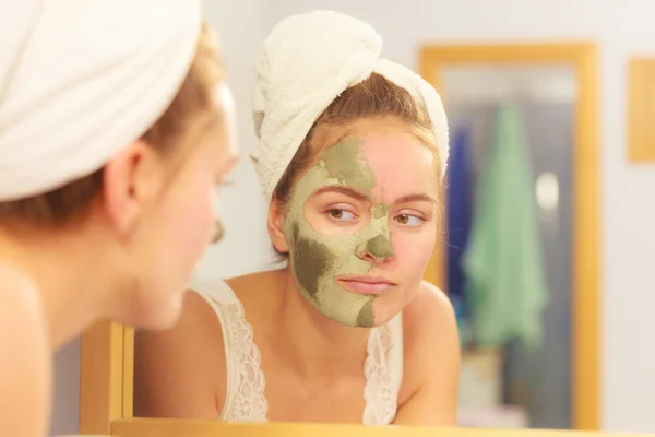 Woman removing facial clay mud mask in bathroom — Stock Photo, Image