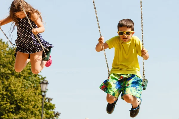 Dwoje dzieci zabawy na swingset. — Zdjęcie stockowe