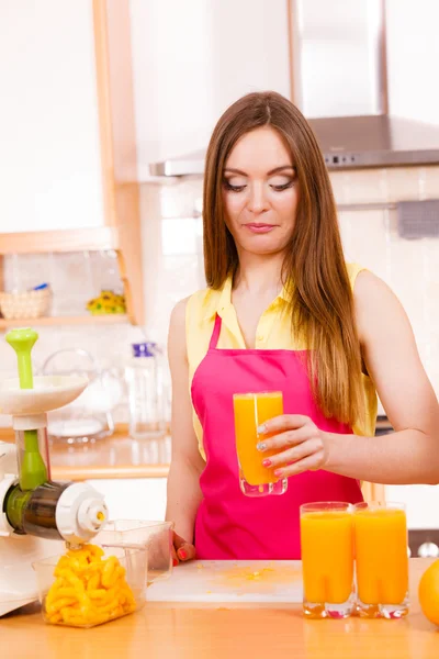 Mulher na cozinha beber suco de laranja fresco — Fotografia de Stock