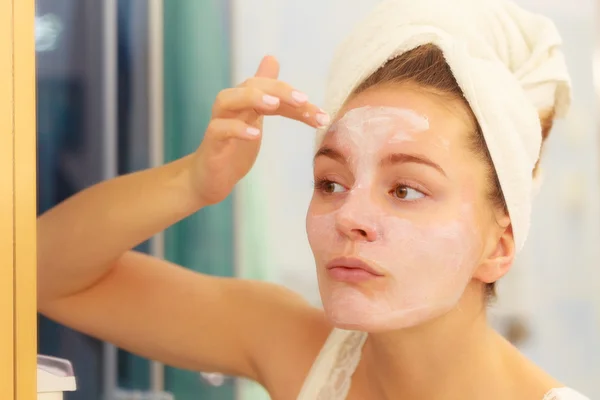 Mujer aplicando crema mascarilla en la cara en el baño — Foto de Stock