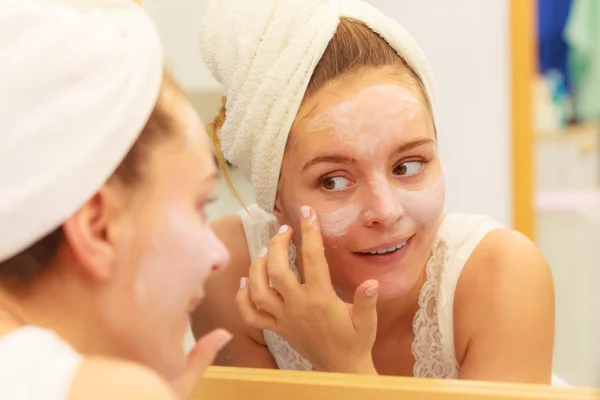 Mujer aplicando crema mascarilla en la cara en el baño — Foto de Stock