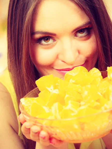 Mujer sostiene cuenco lleno de frutas de naranja en rodajas — Foto de Stock