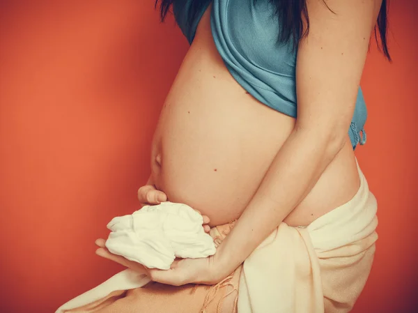 Беременная женщина в маленькой обуви для будущего ребенка — стоковое фото