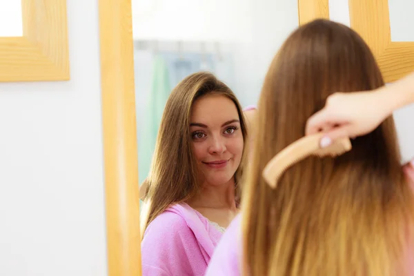 Mulher penteando seu cabelo comprido no banheiro — Fotografia de Stock