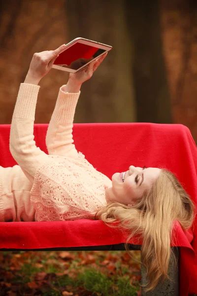 Девушка сидит на скамейке с планшетом . — стоковое фото