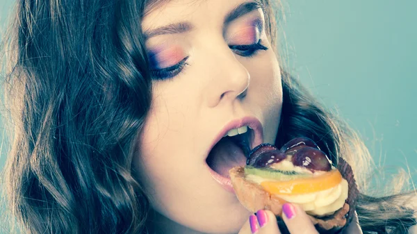 Cute girl holds fruit cake in hand on blue — Stock Photo, Image