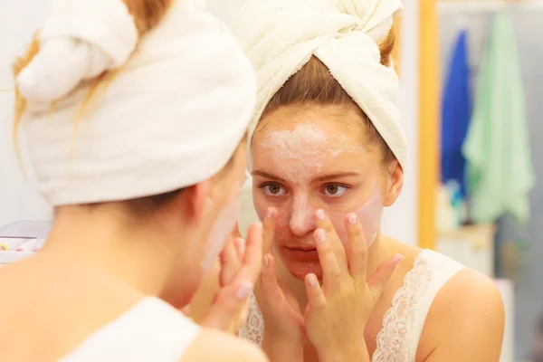 Mujer aplicando crema mascarilla en la cara en el baño — Foto de Stock