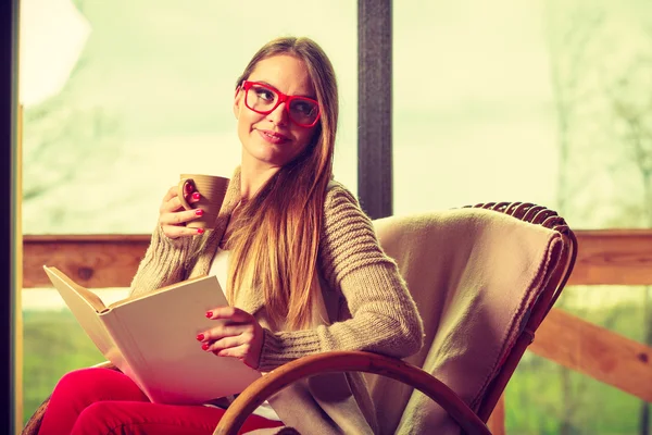 Woman sitting on chair reading book at home — Stock Photo, Image