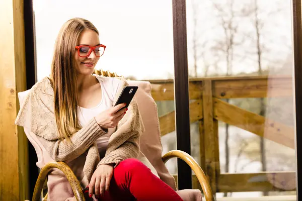 Frau sitzt mit Handy zu Hause auf Stuhl — Stockfoto