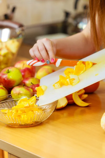 Žena v domácnosti v kuchyni řezání oranžové plody — Stock fotografie