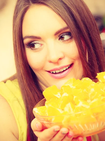 Woman holds bowl full of sliced orange fruits — Stock Photo, Image