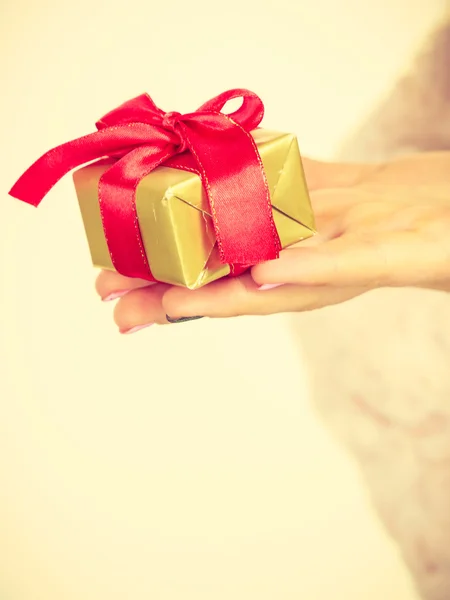 Vrouwelijke hand met gouden doos cadeau — Stockfoto