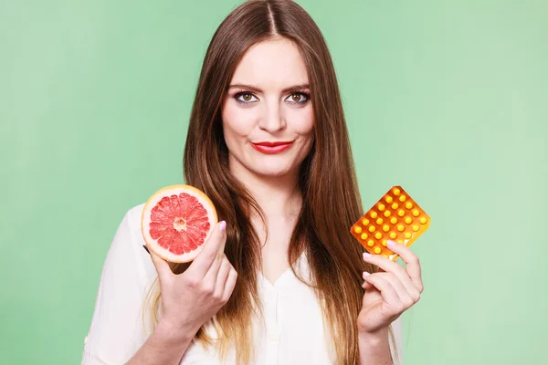 Mujer sostiene pomelo y píldoras blister paquete vitamina c — Foto de Stock