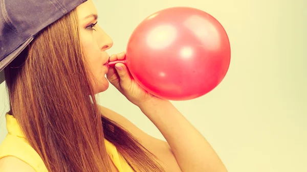 Mujer adolescente inflando globo rojo . — Foto de Stock