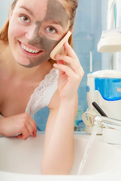 Woman removing facial clay mud mask in bathroom — Stock Photo, Image