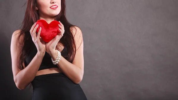 Güzel kadın siyah üzerine kırmızı kalp tutar — Stok fotoğraf