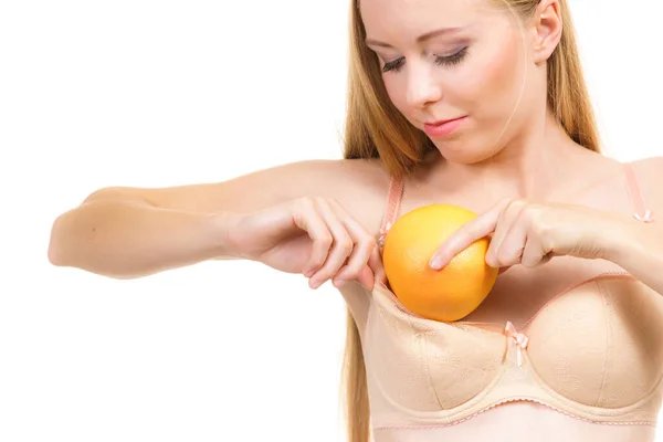 瘦小的年轻女人把大桔子放在胸罩里 扩大乳房尺寸校正概念 — 图库照片