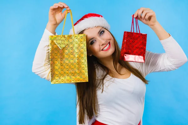 年轻的黑发女人乐于送圣诞礼物 头戴圣诞礼帽的女性带着节日礼品袋 — 图库照片