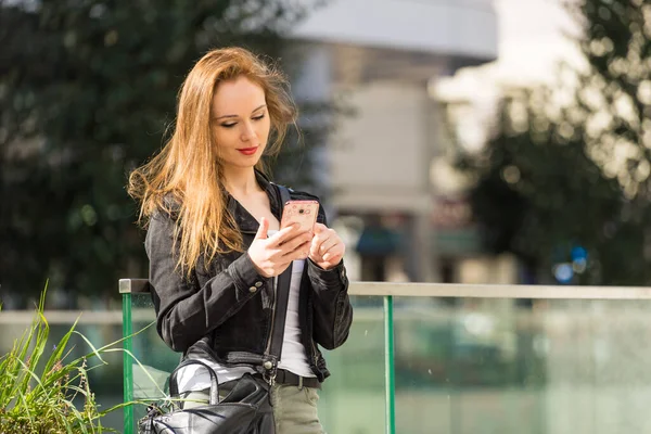 时尚女性穿着时髦休闲装 穿着黑色休闲装 穿着休闲装 在城市户外散步 用手机 — 图库照片