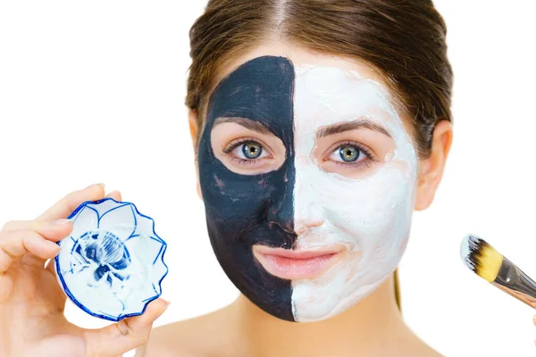 顔の半分に粘土のカルボ黒マスクを持つ女性は 皮膚をきれいにするためにブラシ白い泥で適用されます 女の子は油性の肌の世話をする 美容方法だ スキンケア — ストック写真