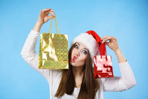 若い大人のきれいな女性はクリスマスのギフトを与えることは幸せである 赤いサンタクロースの帽子をかぶった女性がプレゼントを保持 青の背景 — ストック写真