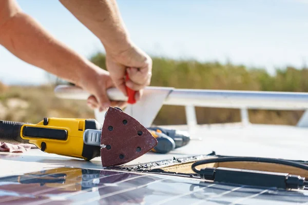 Male hands installing flexible solar panel on rv campervan or repair camper car roof.