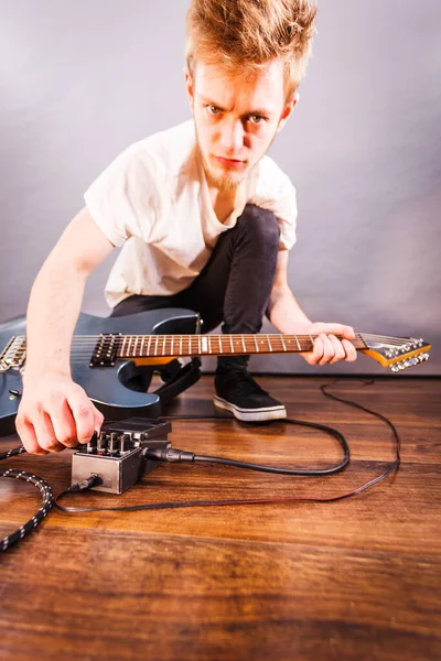Man with musical instrument setting up guitar audio stomp box effects and cables in music studio