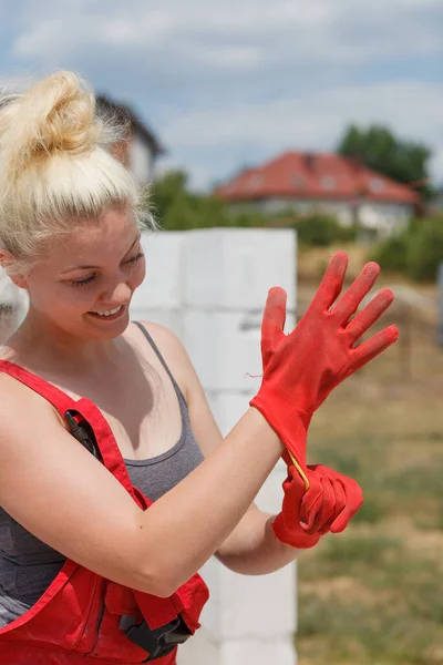 赤い産業安全労働者の手袋を着用している女性は 建設現場で作業をしようとしています — ストック写真