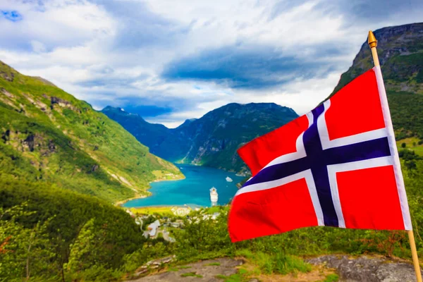 Norwegian flag and beautiful view over Geirangerfjorden from Flydalsjuvet viewing point. Tourist attraction. Tourism vacation and travel.